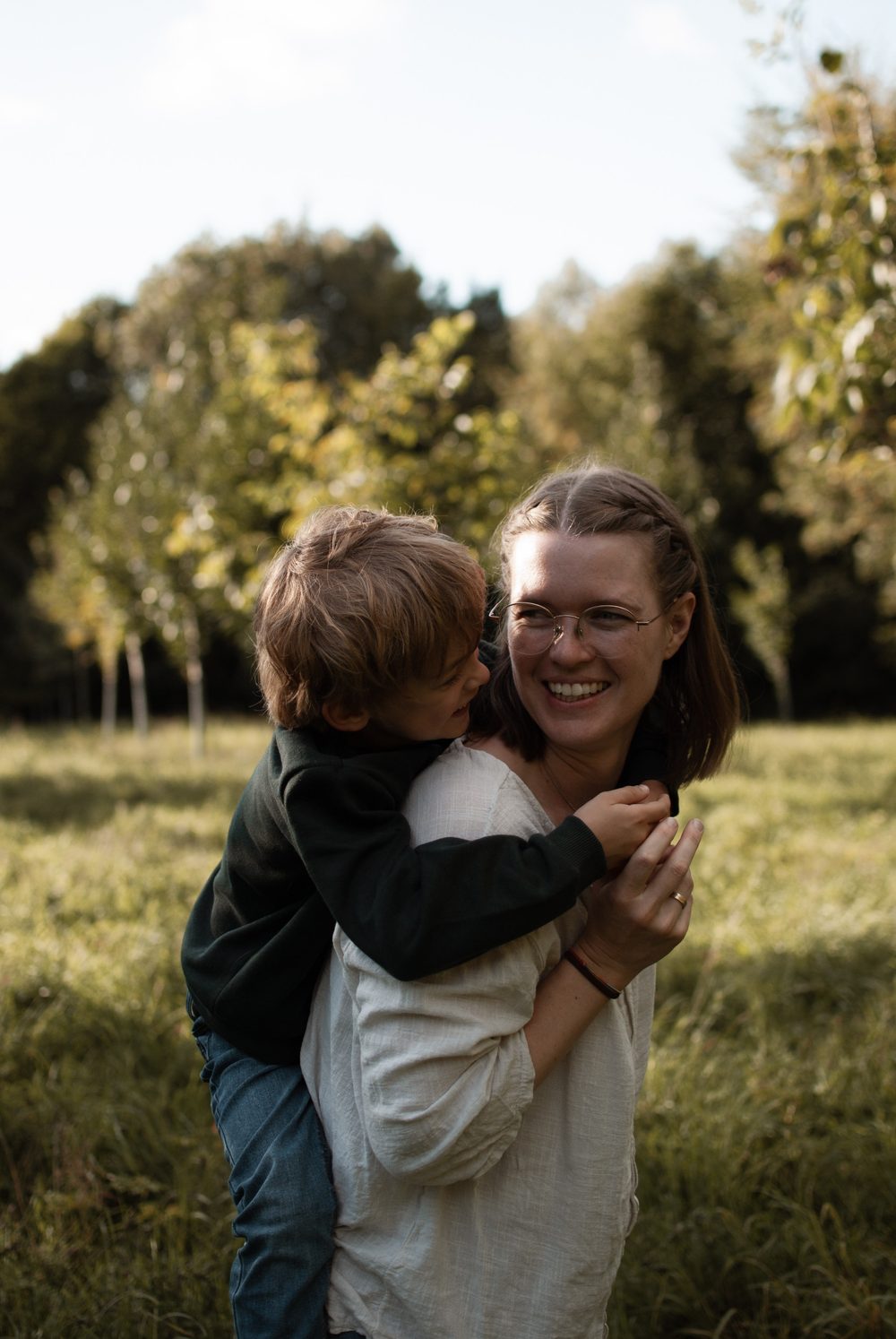 Der Sohn klettert der lachenden Mama auf den Rücken, beide strahlen sich an